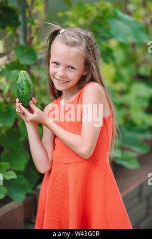 Adorable kleinen Mädchens ernten Gurken und Tomaten im Gewächshaus. Stockfoto