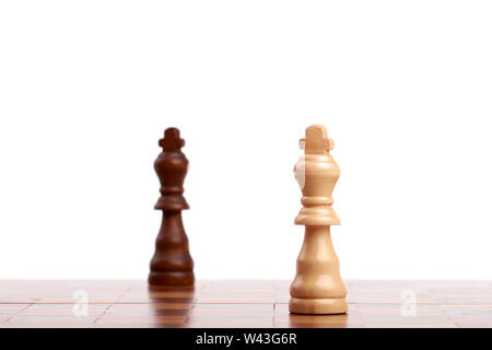 Zwei Holz- Schachfiguren, schwarze und weiße König auf dem Brett. Strategie und Sieg auf weißem Hintergrund. Stockfoto