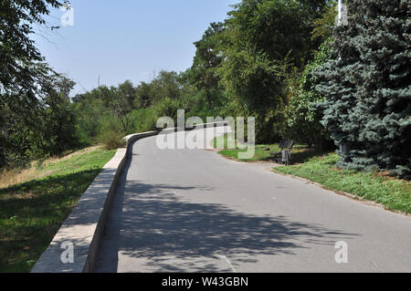 Sommer Park Landschaft mit grünen Bäumen und asphaltierte Straße nach rechts drehen Stockfoto