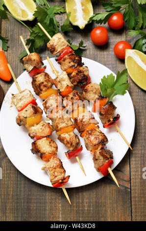 Gegrilltes Hähnchen auf Bambus Spieße. Gemüse und Kräuter auf Holztisch, Ansicht von oben Stockfoto
