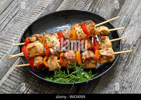 Chicken Kebab mit Paprika in einer Pfanne auf Holztisch, Nahaufnahme Stockfoto