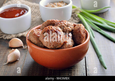 Gebratene Fleischbällchen in Keramik Schüssel auf einen hölzernen Tisch Stockfoto