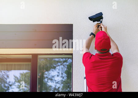 Techniker die Installation im Freien Sicherheit Überwachungskamera auf Haus Außenwand Stockfoto