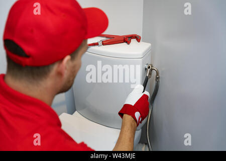 Klempner arbeiten in Wc installieren flexible Leitung zum Tank wc Stockfoto