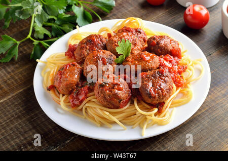Frikadellen und Spaghetti auf weißem Schild auf hölzernen Tisch Stockfoto
