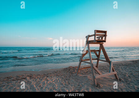 Strand mit Holz- Rettungsschwimmer Stuhl im Sonnenuntergang. Stockfoto