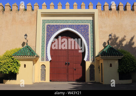 Marokko, Fes. Schöne defensive Wand und Fassade, mit Arabesque stil Torbogen und glasierte Fliesen Tür Surround mit islamischen symmetrische Muster. Stockfoto