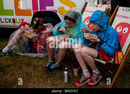 Festivalbesucher Unterschlupf vor dem Regen bei Latitude Festival, henham Park, Suffolk, Großbritannien am 19. Juli 2019 Stockfoto