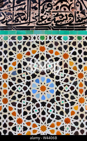 Fez, Marokko. Detail eines alten Terrasse Wand mit Glasierte keramische Fliesen in islamischen Stil Mosaik und Arabische Kalligraphie eingerichtet. Stockfoto