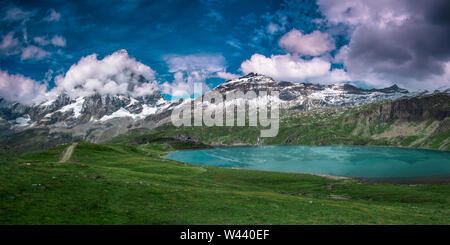 Panoramablick auf die Südseite des Matterhorns, Ansicht von Plan Maison. Grüne Wiese und einem kristallklaren See im vorderen, blauer Himmel mit weißen Wolken Stockfoto