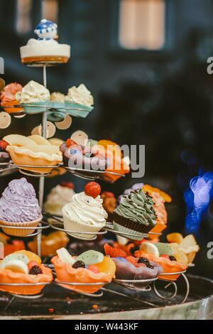 Nahaufnahme einer Vielzahl von leckeren Cupcakes auf einem Metall Dekorativer Ständer mit verschwommenem Hintergrund Stockfoto