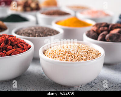 Quinoa Korn in der kleinen weißen Schale und andere superfoods für den Hintergrund. Selektive konzentrieren. Verschiedene superfoods Zutaten. Konzept und Grafik für superfood und entgiftende Lebensmittel Stockfoto