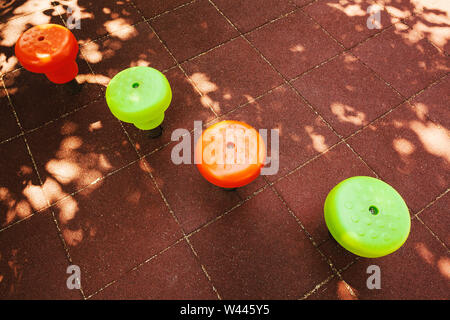 Teil des Park Spielplatz, grün und orange Laufflächen auf gummierter Oberfläche. Stockfoto