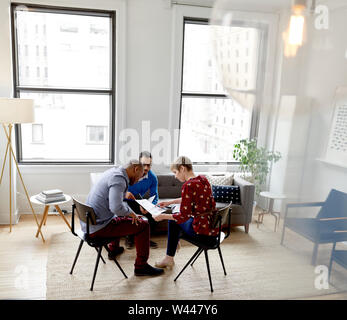 Vielfältige Gruppe von jungen kreativen Entwickler Ideen diskutieren und zur Festlegung der Dokumente während eines Brainstormings Stockfoto