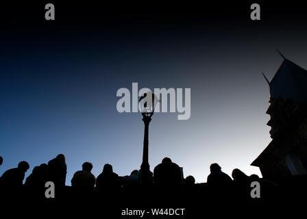 Prag, tschechische Republik - 7. Oktober 2008: Eine Masse von Touristen in der Dämmerung auf einer Brücke ruht, silhouetted Bilder Hintergrundbeleuchtung gegen eine Straßenlaterne. Stockfoto