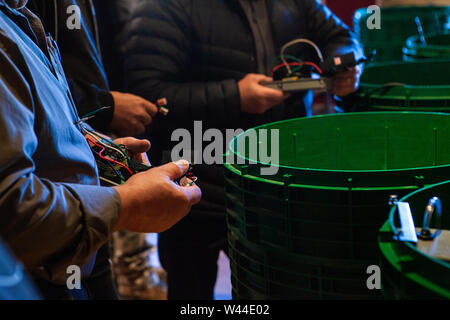 Zwei Menschen mit Jacken auf sind Anschlussleitungen in die D-Box während einer ökologischen septischen Schulungen für Unternehmer und Fachleute, mit Händen in der Nähe gesehen. Stockfoto