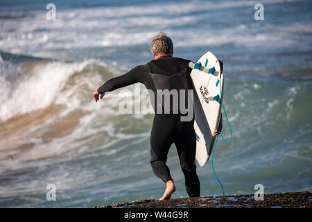 Australischer Mann trägt sein Surfbrett zum Ozean für ein Surfen auf den Wellen des Ozeans, Avalon Beach, Sydney, Australien Stockfoto
