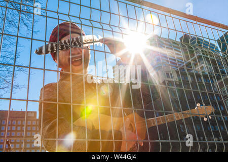 Eine Nahaufnahme und Low Angle View eines spirituellen Musiker stehen in der Innenstadt, mit einem Merlin Gitarre und das Gesicht mit einer nativen Eagle Feather während des s Stockfoto