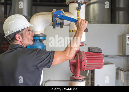 Heizungs-/Lüftungs-/Mechaniker arbeiten an ein Ventil im Inneren des Kessels Zimmer Stockfoto
