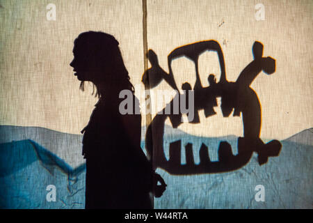 Ein Mädchen gesehen steht von einem Monster während einer Schule Produktion, warfen Silhouetten auf ein Tuch während einer Schule spielen. Stockfoto