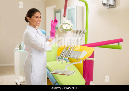 Schönen lächeln Kaukasischen Ärztin aseptische Handschuhe tragen Stockfoto