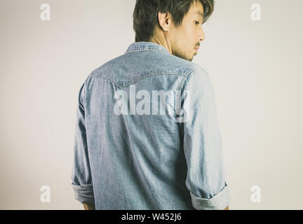 Porträt Mann in Jeans Shirt oder Jeans Shirt Mode in der Rückansicht. Denim Jeans Hemd oder T-Shirt Mode für Männer auf grauem Hintergrund Stockfoto