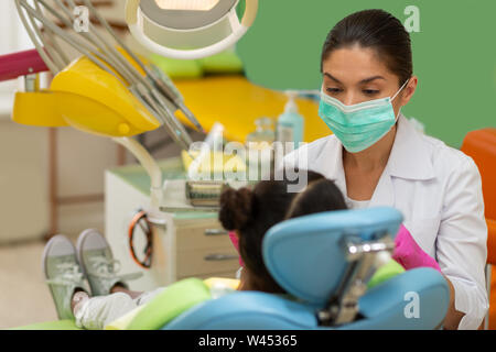 Dunkelhaarige Patientin in einem Zahnarztstuhl sitzen Stockfoto