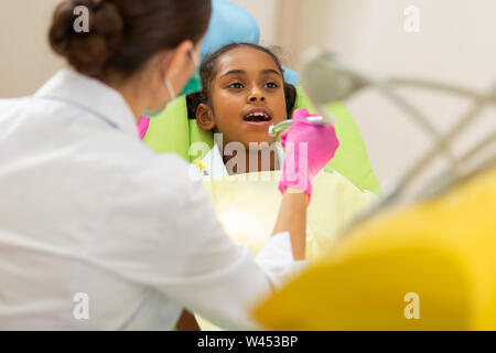 African American Girl in einem Zahnarztstuhl sitzen Stockfoto