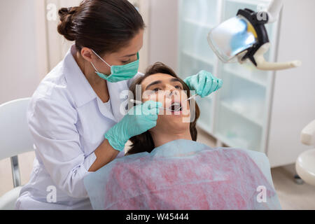 Konzentrierte sich Frau Zahnarzt beugte sich über Ihre männlichen Patienten Stockfoto