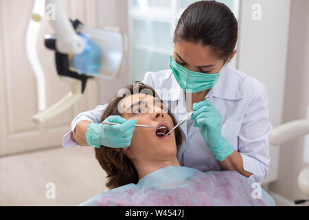 Weiblichen Zahnarzt in einem männlichen Patienten öffnung suchen Stockfoto