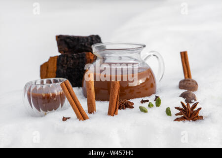 Eine Detailansicht der Zutaten und frisch gebrühten chaga Chai Tee, einem warmen Getränk traditionell im Winter, mit Arzneimitteln chaga Pilzen und Gewürzen Stockfoto