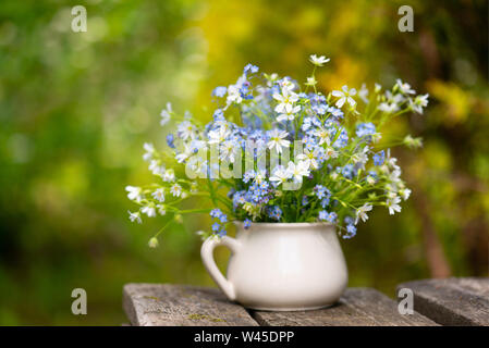 Blumenstrauß aus zarten frischen Blumen auf die texturierte Holztisch Stockfoto