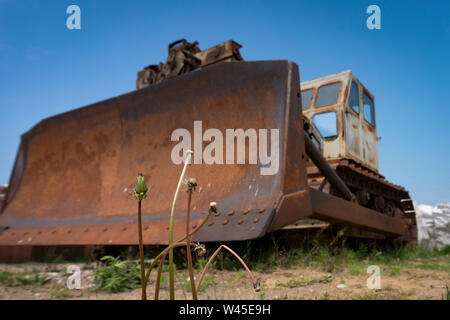 Low Angle View eines alten rostigen Heavy Duty Industrial digger oder Sortierer geparkt, im Freien in einem Feld unter einem bewölkten Himmel Stockfoto