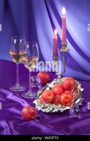 Zwei Gläser, Aprikosen und Kerzen auf der Fabric studio Hintergrund Stockfoto