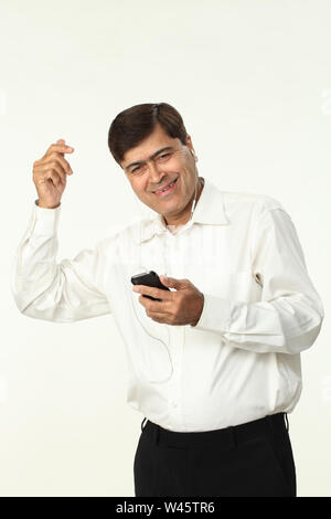 Geschäftsmann, der Musik auf einem Mobiltelefon hört Stockfoto