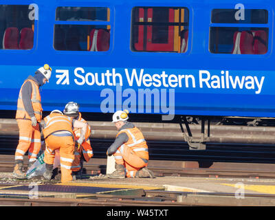 Clapham Junction, London, UK, 14. Februar 2019; Gruppe von Schiene Arbeiter Arbeiten an der Rennstrecke mit South Western Railway Zug hinter Stockfoto