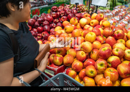 Asiatische Frau Kommissionierung Apple am Obststand in Lebensmittelgeschäft Stockfoto