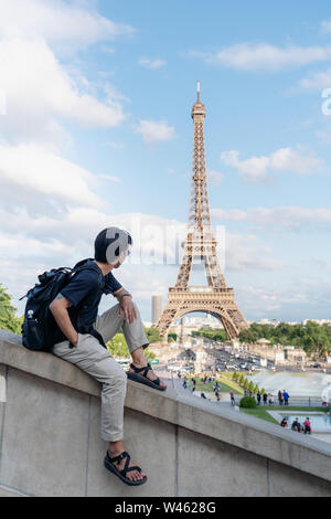 Unterwegs in Europa im Sommer, ein Mann mit Rucksack am Eiffelturm suchen, Wahrzeichen und Reiseziel in Paris, Frankreich Stockfoto