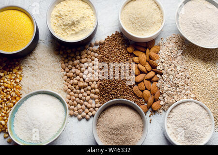 Verschiedene glutenfreie Mehl - Kichererbsen, Reis, Buchweizen, Quinoa, Mandeln, Mais, Haferflocken auf grauem Hintergrund. Stockfoto