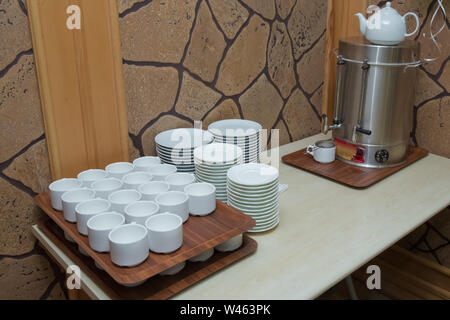 Becher für Kaffee und Tee auf dem Bankett. Die selbst-Station dienen. Kaffee, Zucker, Sahne sowie Geschirr und Besteck. Thermoskanne mit heißem Wasser und Tassen. Stockfoto