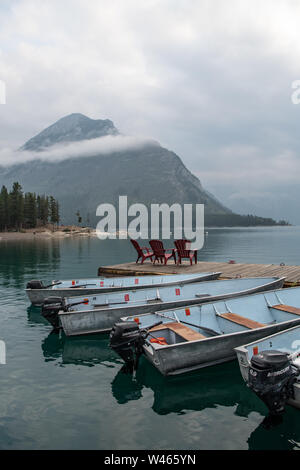 Porträtblick auf Lake Minnewanka, Banff, mit reflektierten Booten im Vordergrund und Bergen hinter Alberta, Kanada Stockfoto