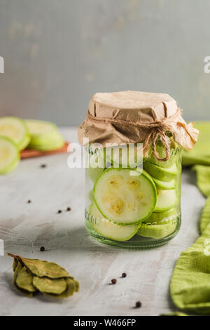 Fermentierte Zucchini in ein Glas Gewürze auf einem hellen Hintergrund close-up mit Copyspace. Ernte von Gemüse für eine gesunde Ernährung. Stockfoto