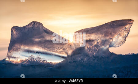 Schönes transparentes Eis des Baikalsees gegen das Dunkelblau Orangefarbener Himmel und eine strahlende Sonne Stockfoto