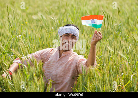 Bauer hält eine indische Flagge und lächelt Stockfoto