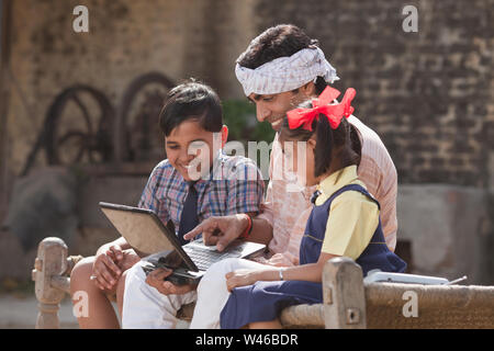 Mann mit Laptop mit seinen Kindern Stockfoto