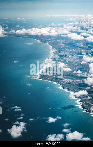 Flug über die Küste von Portugal Lissabon Region. Luftaufnahme durch das Flugzeug Fenster mit Wolken, Wasser und die Küste. Stockfoto