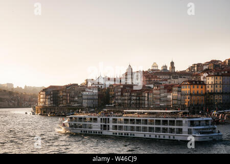 Die Altstadt von Porto am Fluss Douro mit touristischen Boote und Fähren bei Sonnenuntergang, Portugal. Stockfoto