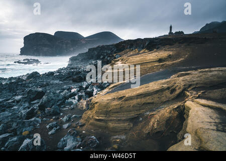 Blick über den Vulkan Capelinhos, Leuchtturm von Ponta Dos Capelinhos auf der westlichen Küste auf die Insel Faial, Azoren, Portugal mit einem dramatischen Sonnenuntergang und stark Stockfoto