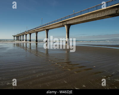 Modern New Brighton Pier, Neuseeland Südinsel, Im rippled nassen Sand mit blauen Himmel hinter wider Stockfoto