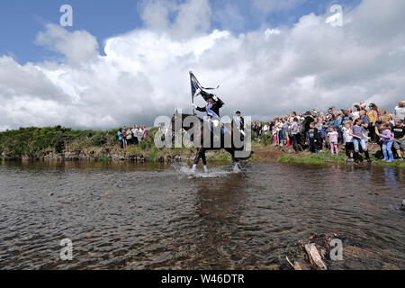 Kelso, Schottland, Großbritannien. Juli 2019 20. Kelso Civic Woche - yetholm Ride Out, Kelso. Kelso Laddie Mark Henderson trägt die Stadt Flagge (Standard), wie Er durchschreitet die Bowmont Wasser vor der 200 starke montiert Kavalkade mit RHM Sean Haken (2018 KL), Craig Logan (2017-KL), auf der Fahrt zu Yetholm Samstag, 20. Juli 2019. (Bild: Rob Grau): Rob Grau/Alamy leben Nachrichten Stockfoto